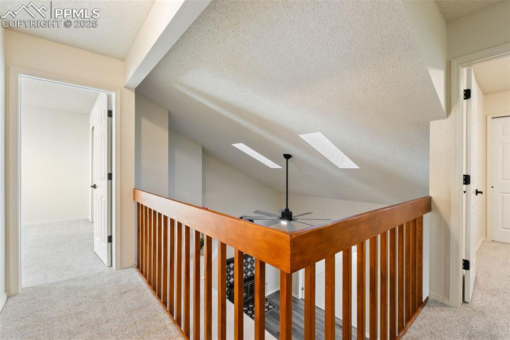 Image 31 of 50: Hall featuring light colored carpet, a textured ceiling, a skylight, and va