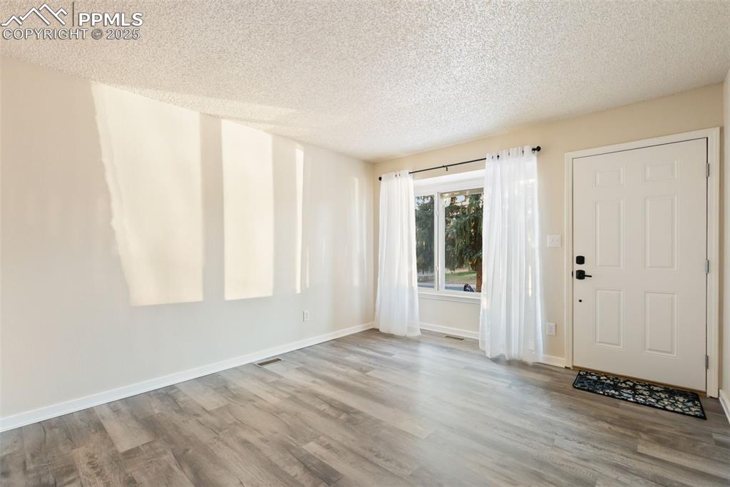 Image 32 of 50: Entryway with a textured ceiling and wood finished floors