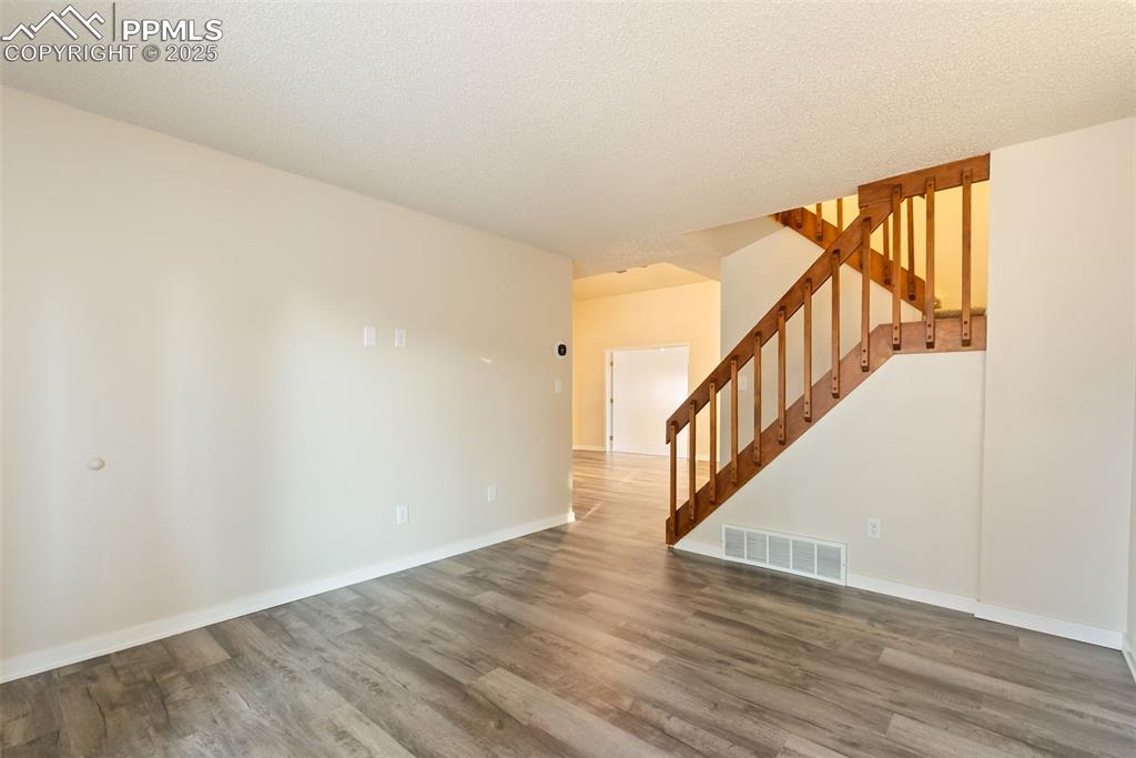 Image 33 of 50: Spare room with stairs, wood finished floors, and a textured ceiling