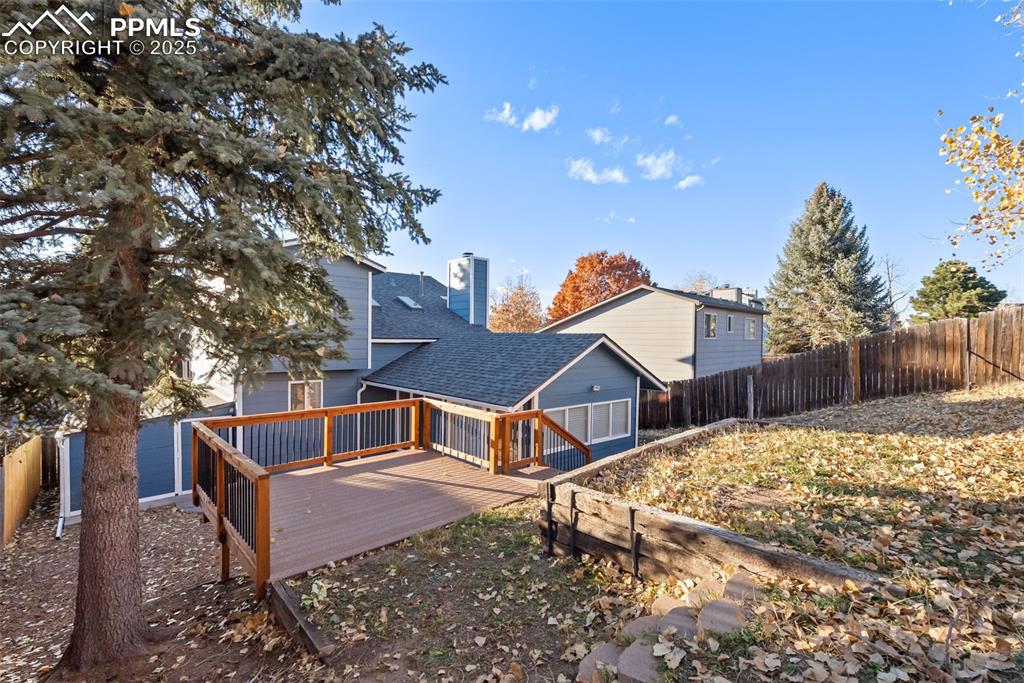 Image 38 of 50: Rear view of property featuring a fenced backyard, roof with shingles, a wo