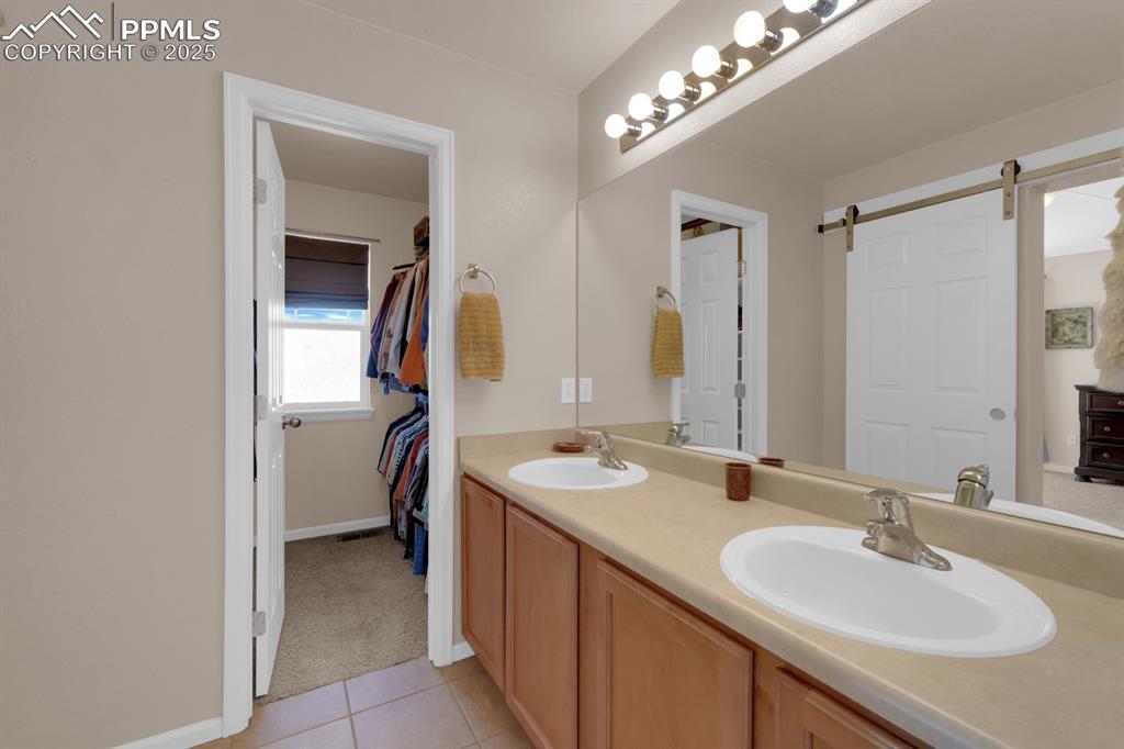Image 19 of 43: En-Suite Full bathroom with double vanity, tile floors, and walk-in closet