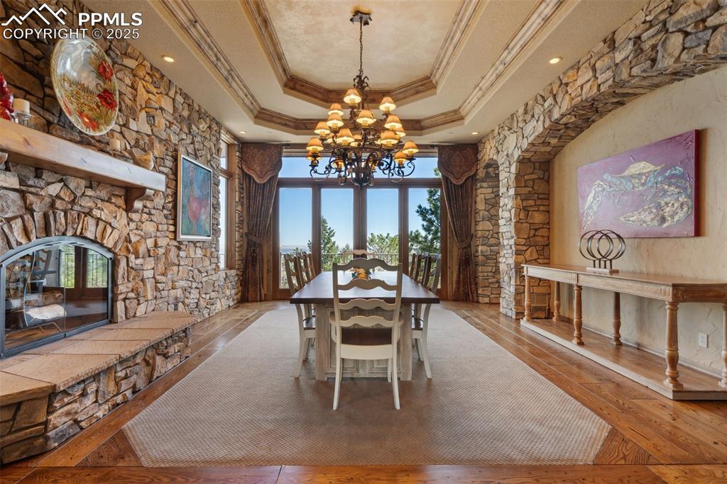 Image 7 of 50: Dining room with wood burning stone fireplace, double tray ceiling with cro