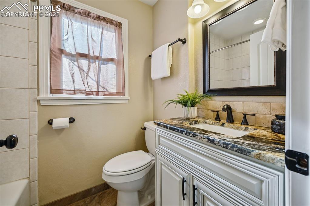 Image 15 of 31: Full bathroom on the main level has tub shower combo, granite countertops,