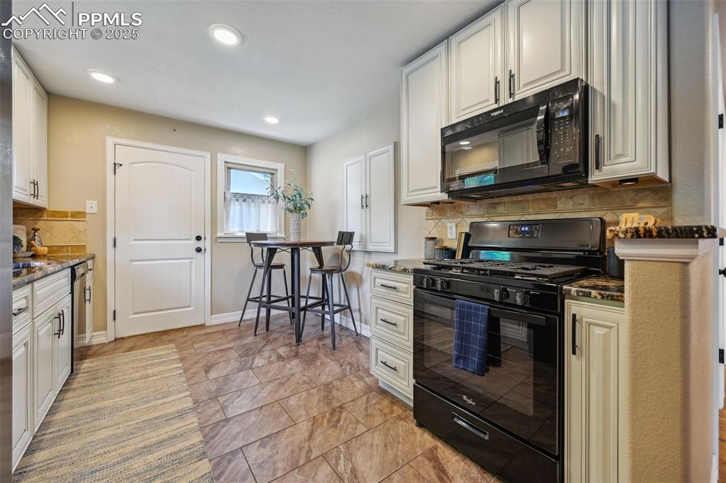 Image 8 of 31: The kitchen features: granite countertops, gas stove, soft close cabinetry,