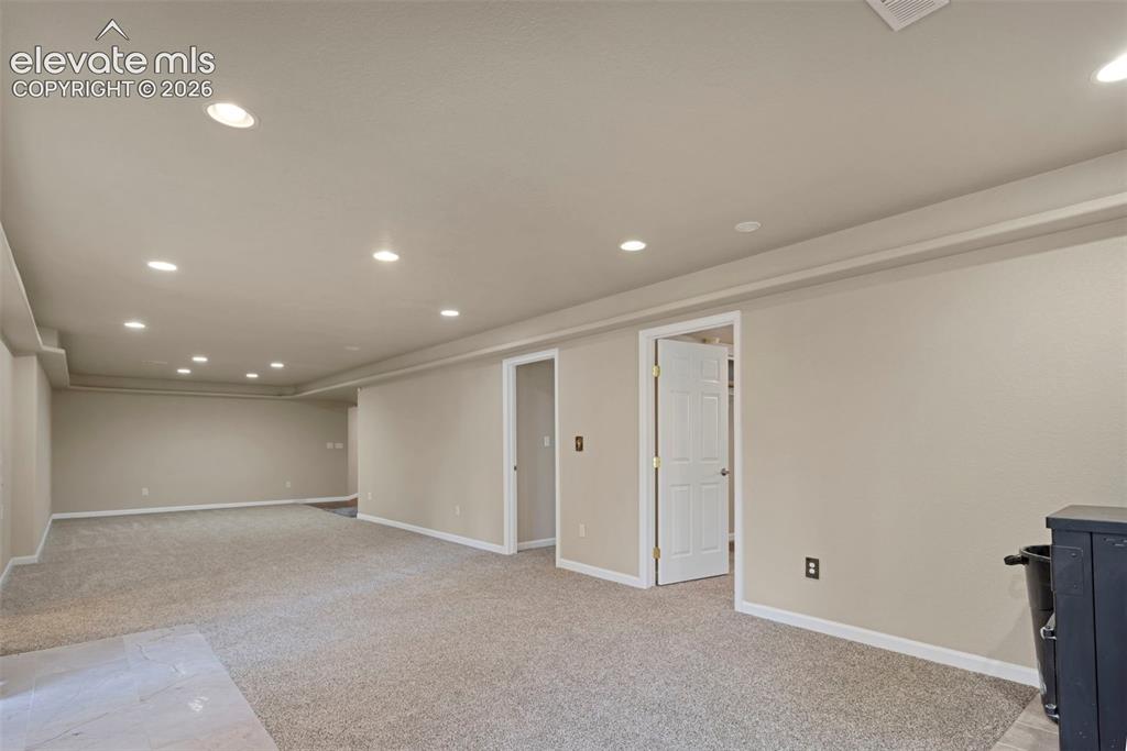 Image 23 of 28: Basement open area with doors to bedrooms