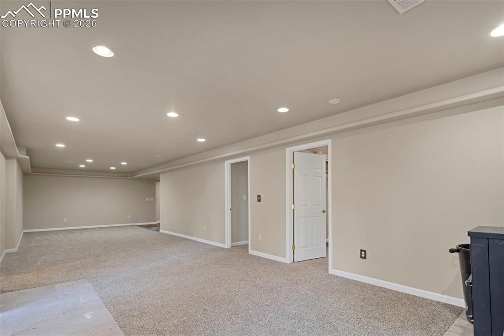 Image 25 of 30: Basement open area with doors to bedrooms