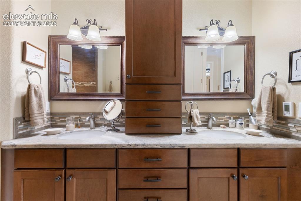 Image 12 of 28: Double vanity featuring individual sinks and mosaic tile backsplash