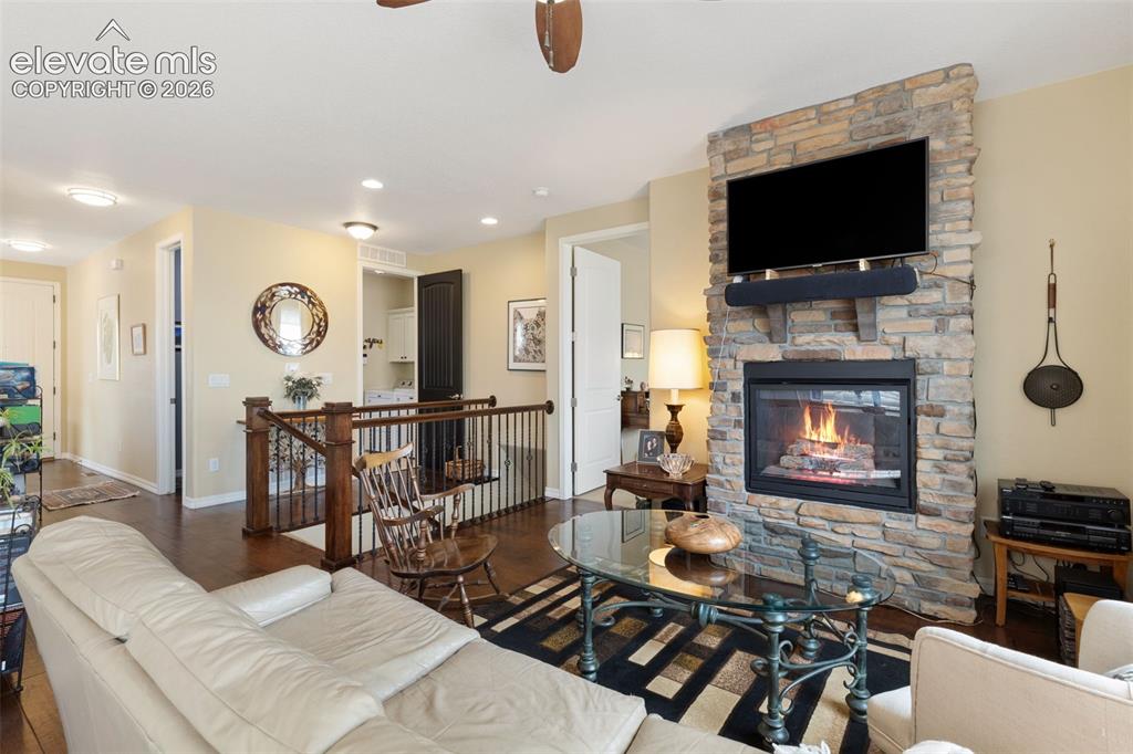 Image 16 of 28: Living area featuring a stone-clad fireplace with a hearth, dark wood-finis