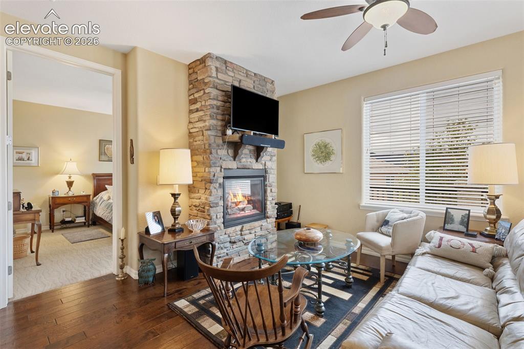 Image 17 of 28: Living area featuring a floor-to-ceiling stone fireplace, hardwood flooring