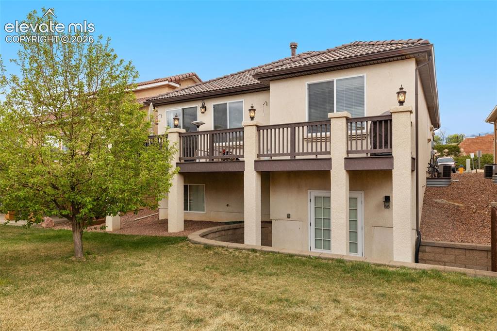 Image 2 of 28: Stucco exterior with a tiled roof and French doors opening to lower patio.