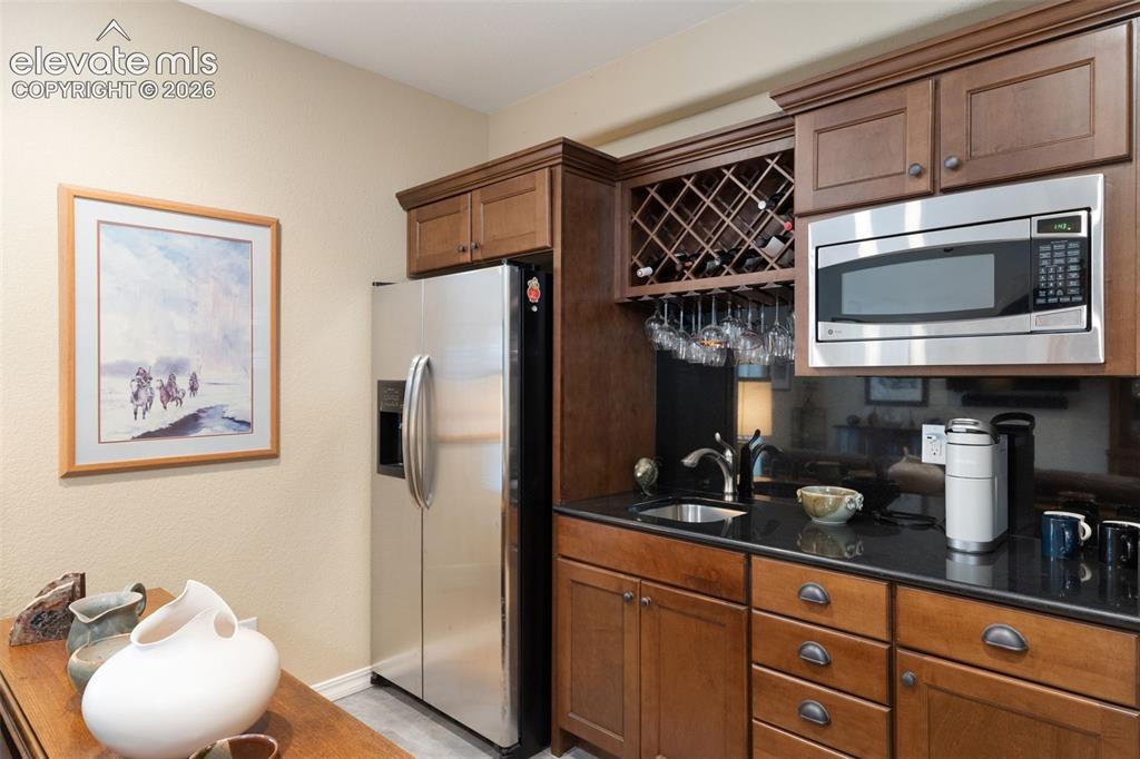 Image 23 of 28: Wet bar featuring a stainless steel microwave, built-in wine rack with stem