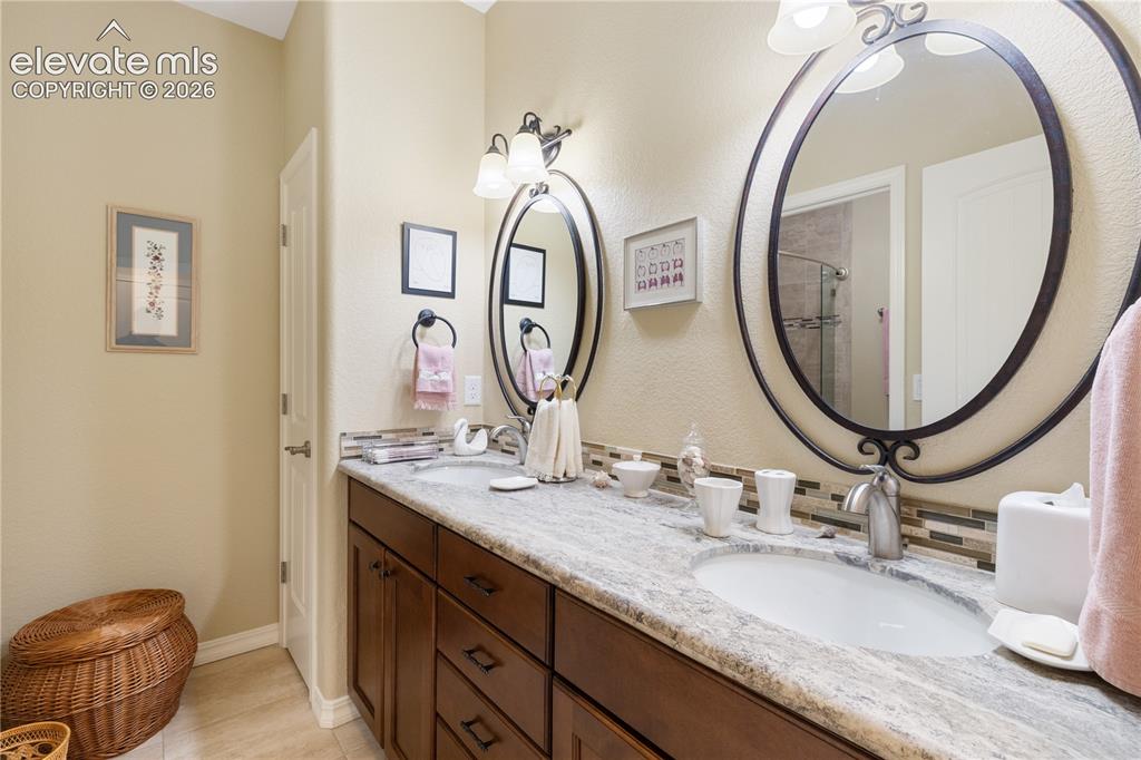 Image 26 of 28: Lower bathroom with dual vanities, shower/tub combo, toilet.