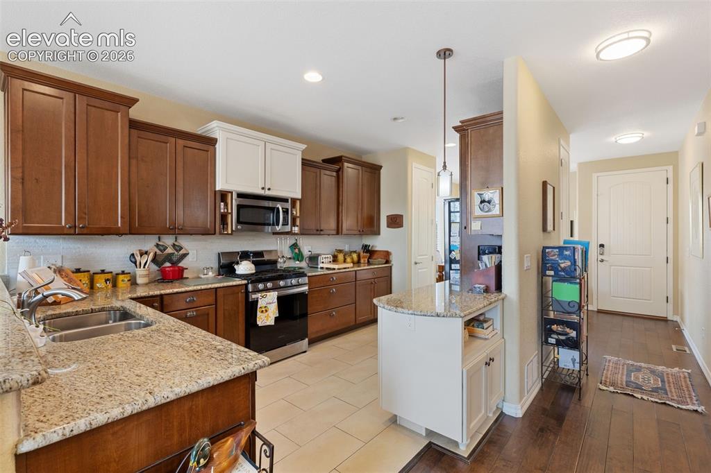 Image 5 of 28: Kitchen featuring granite countertops, stainless steel appliances, and wood