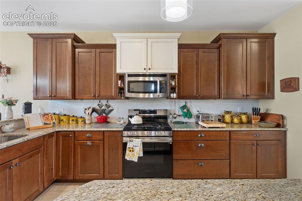 Image 7 of 28: Well-appointed kitchen featuring a stainless steel gas range, built-in micr