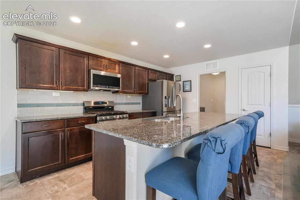 Image 10 of 50: Kitchen with large island, granite countertops, gas range, abundant cabinet