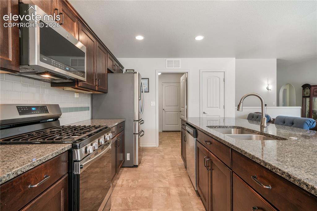 Image 11 of 50: Kitchen with large island, granite countertops, gas range, abundant cabinet
