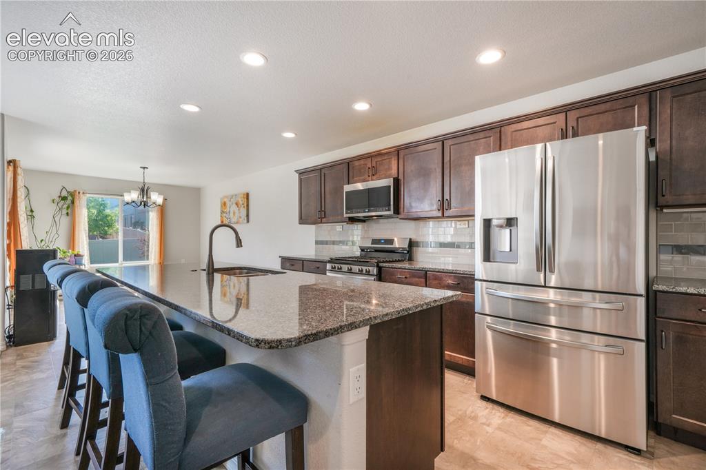 Image 15 of 50: Kitchen with large island, granite countertops, gas range, abundant cabinet