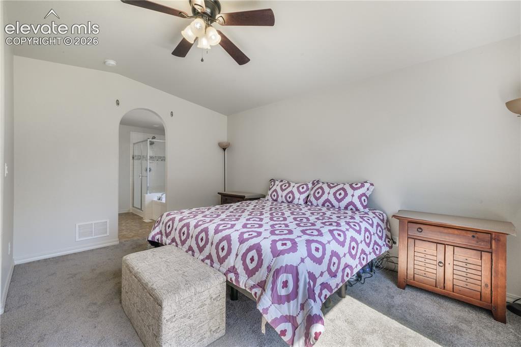 Image 18 of 50: Main level primary bedroom with ensuite 5 piece bathroom with granite count