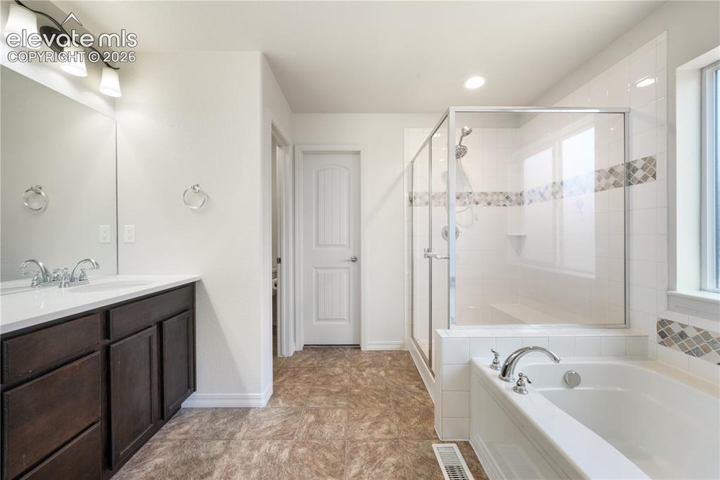 Image 20 of 50: Main level primary 5 piece bathroom with dual sinks, granite counters, free