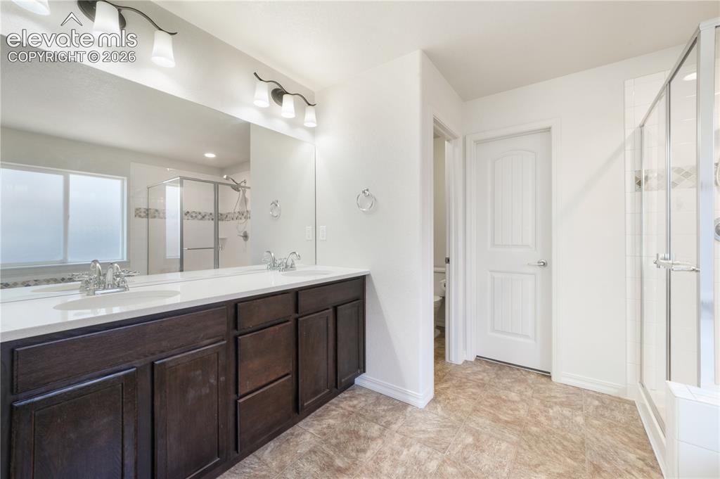 Image 21 of 50: Main level primary 5 piece bathroom with dual sinks, granite counters, free