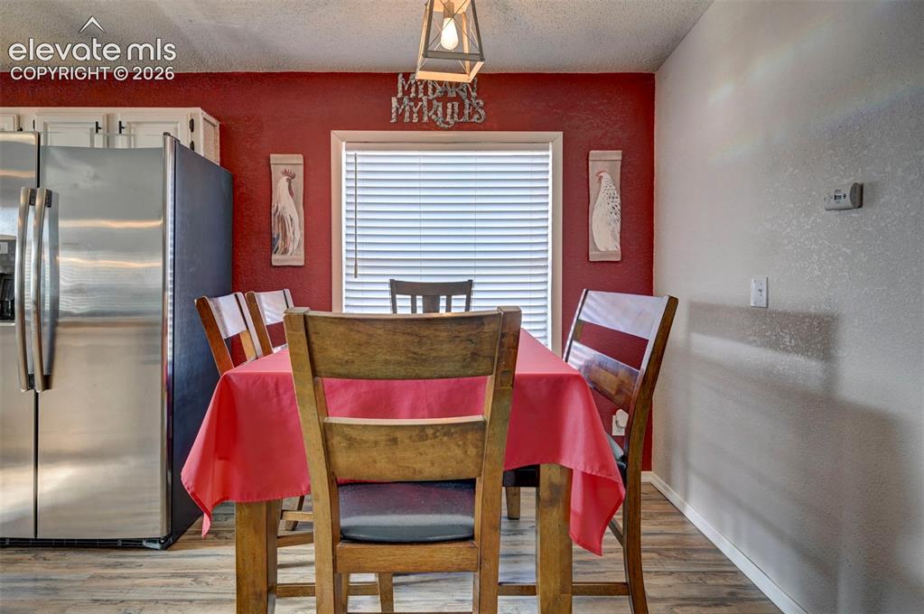 Image 13 of 31: Dining space with light wood-type flooring, a textured wall, and a textured