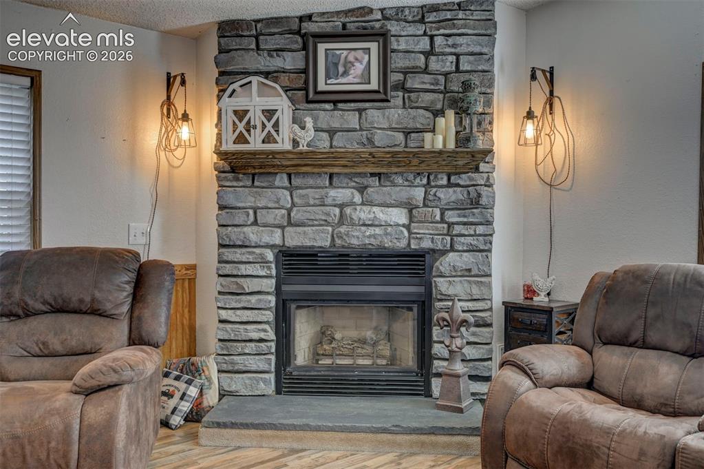 Image 17 of 31: Living room featuring wood finished floors, a textured ceiling, a fireplace