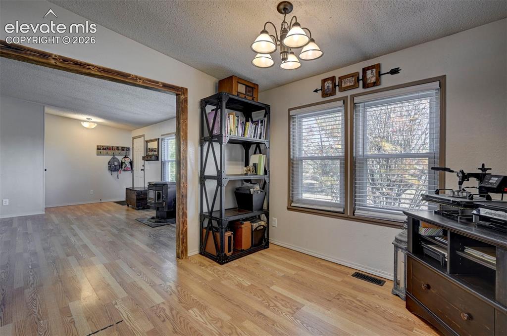 Image 18 of 31: Home office with a textured ceiling, a wood stove, light wood-style floorin