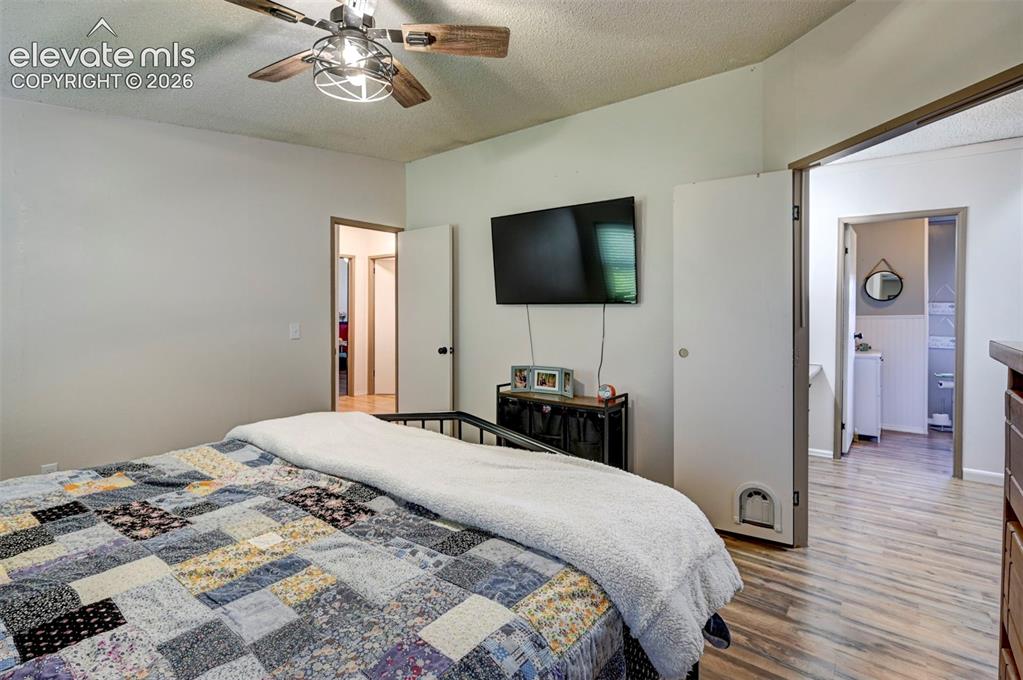 Image 19 of 31: Bedroom with a textured ceiling, light wood finished floors, and ceiling fa