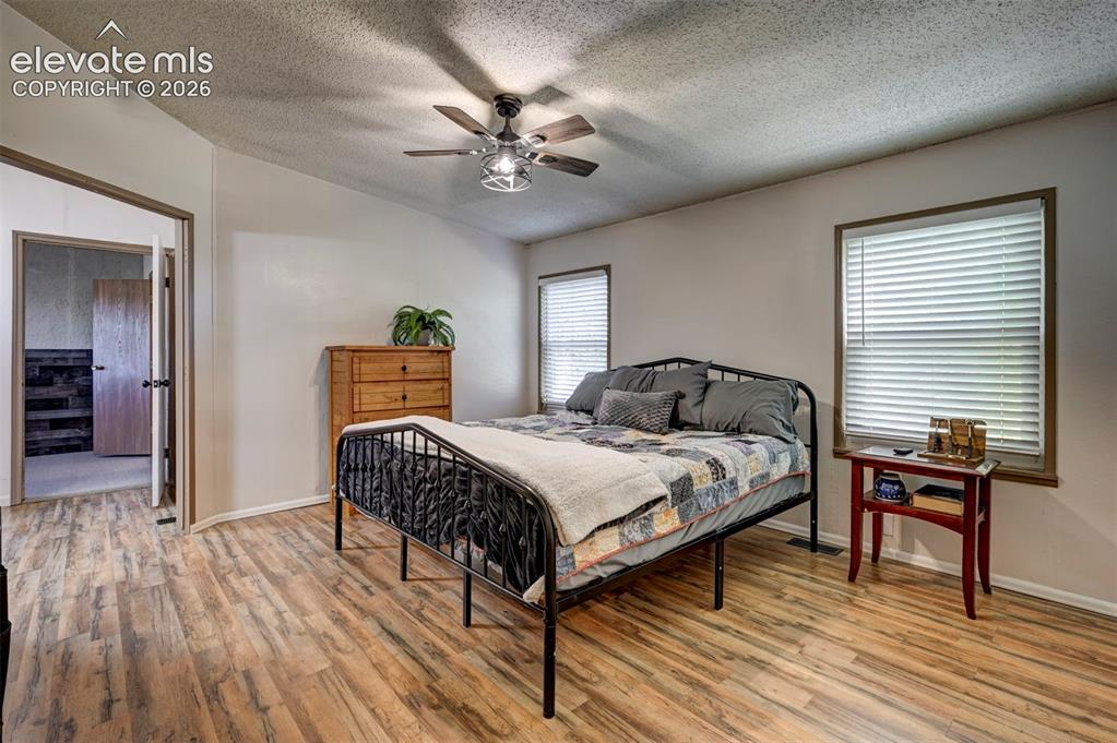 Image 20 of 31: Bedroom with light wood-style flooring, a textured ceiling, and ceiling fan