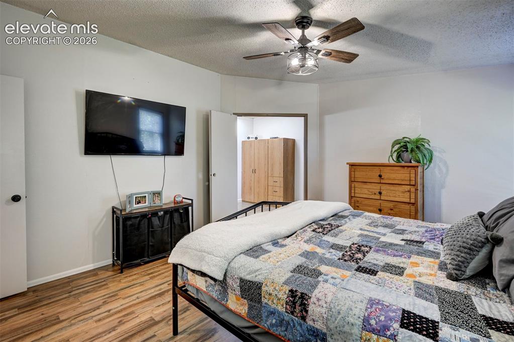 Image 21 of 31: Bedroom with wood finished floors, a textured ceiling, and a ceiling fan