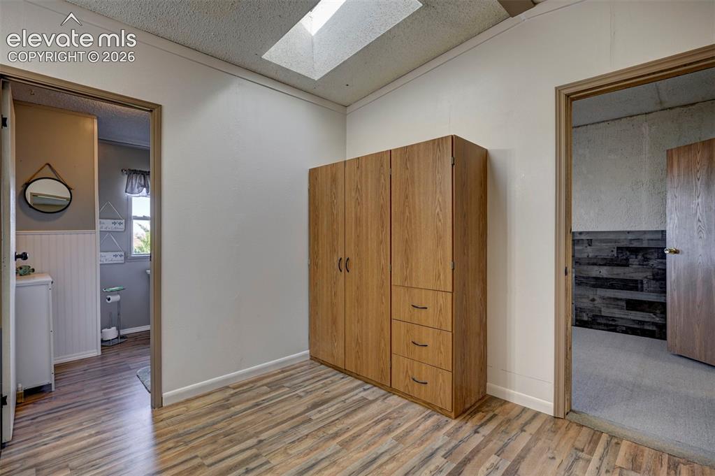 Image 22 of 31: Bedroom featuring light wood-style floors, a skylight, a textured ceiling,