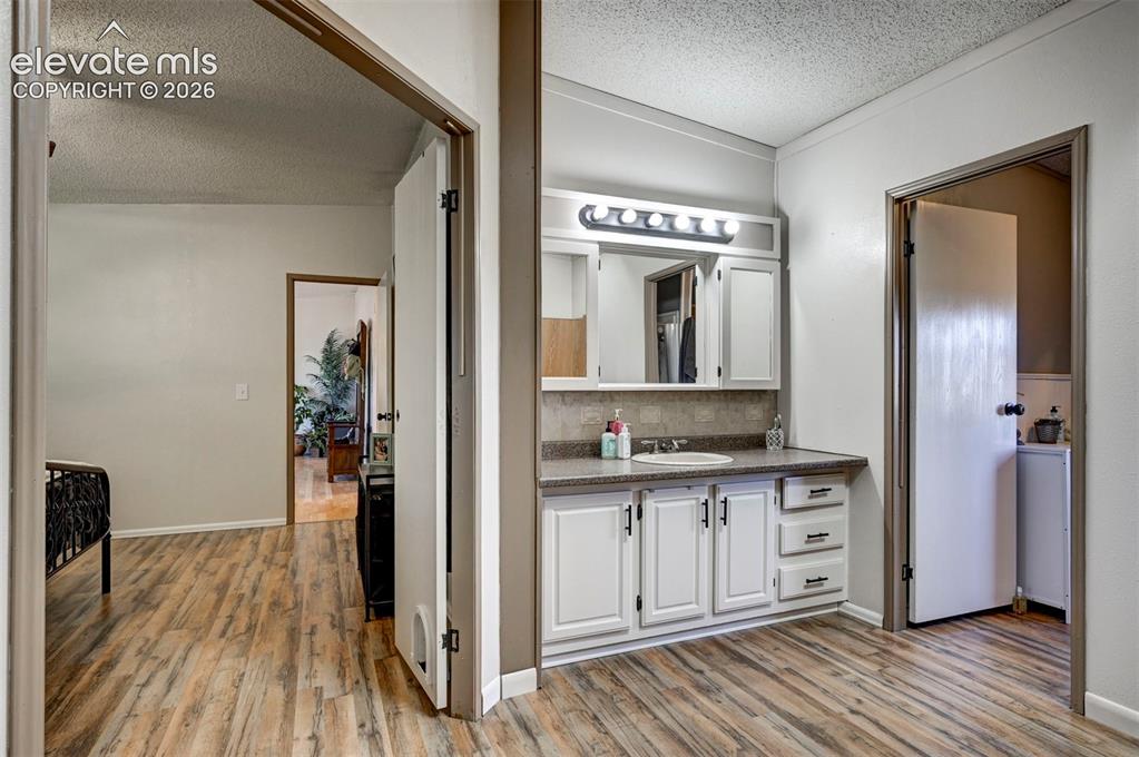 Image 23 of 31: Bathroom with a textured ceiling, light wood-style floors, vanity, and deco