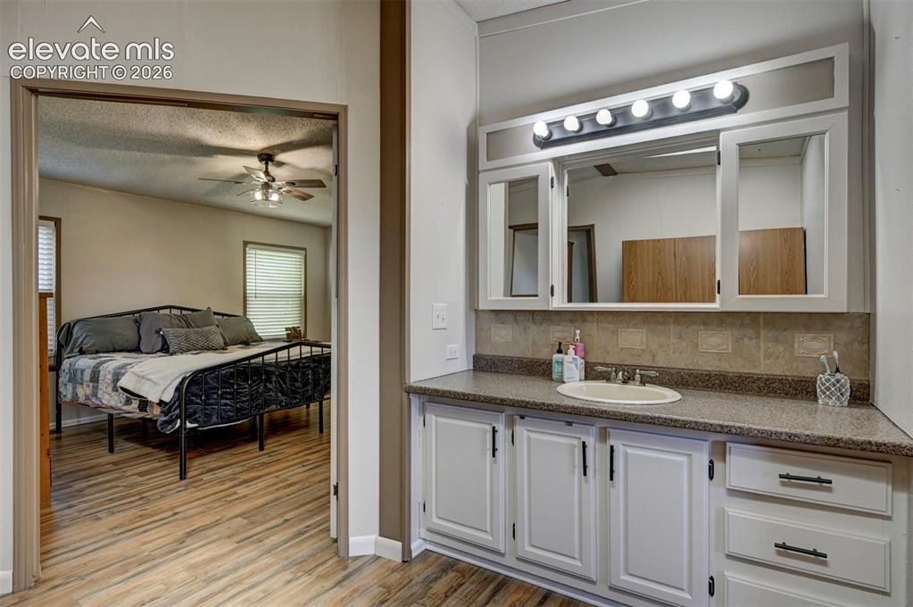 Image 25 of 31: Ensuite bathroom with a textured ceiling, vanity, backsplash, light wood-st