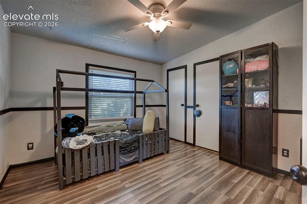 Image 26 of 31: Bedroom with a textured wall, a textured ceiling, a ceiling fan, and wood f