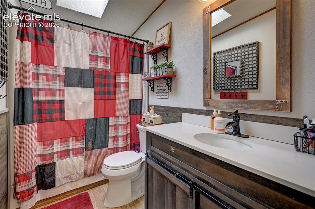 Image 27 of 31: Full bath featuring a skylight, shower / bath combo, vanity, light wood-sty