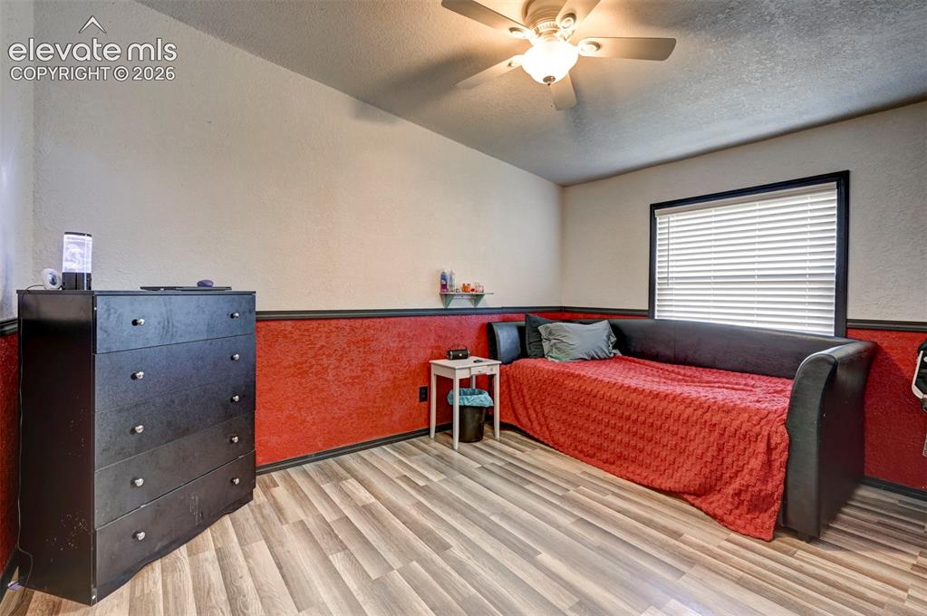 Image 28 of 31: Bedroom featuring wood finished floors, ceiling fan, a textured wall, a tex