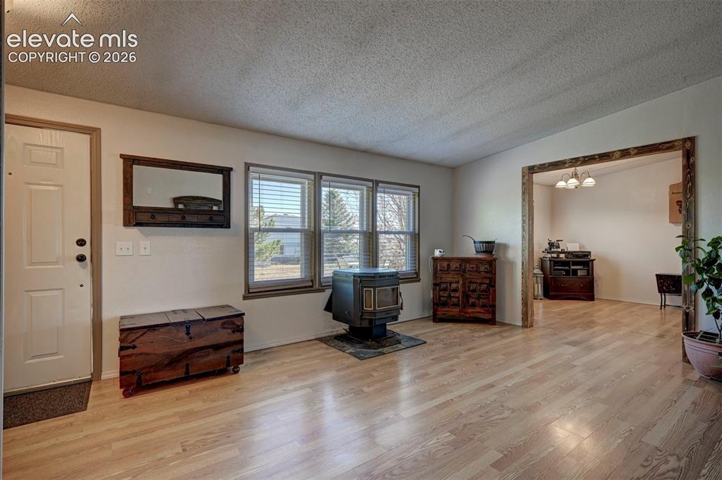 Image 6 of 31: Living area featuring a textured ceiling, wood finished floors, a wood stov
