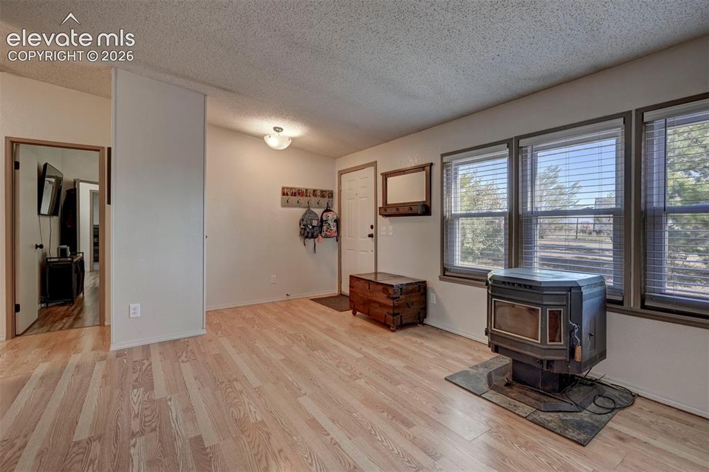 Image 7 of 31: Entrance foyer with a wood stove, a textured ceiling, and light wood-style