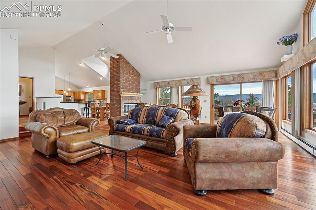 Image 15 of 49: Living room with high vaulted ceiling, wood flooring, and a fireplace
