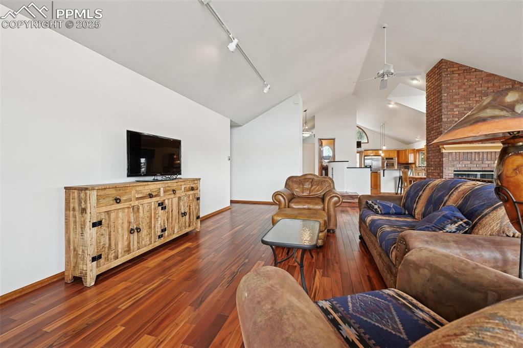 Image 16 of 49: Living area with rail lighting, dark wood-style flooring, a fireplace, high