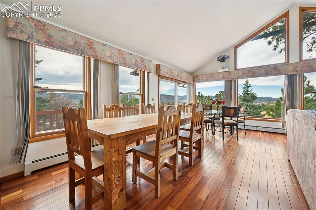 Image 19 of 49: Dining space with light wood-type flooring, high vaulted ceiling, and a bas