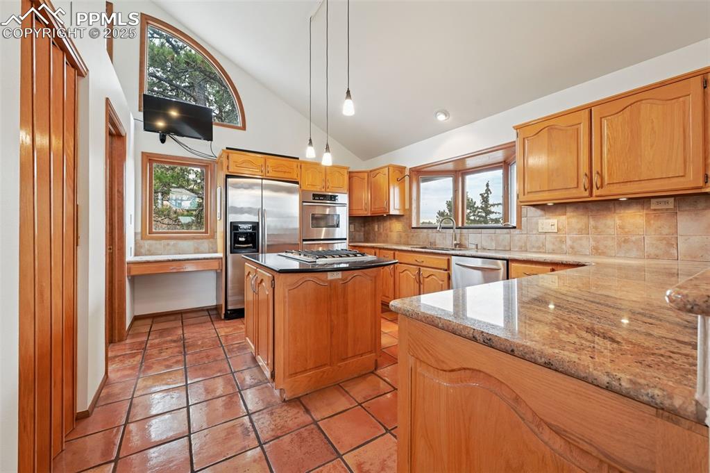 Image 22 of 49: Kitchen w/tile backsplash, pendant lighting, stone countertops, appliances 