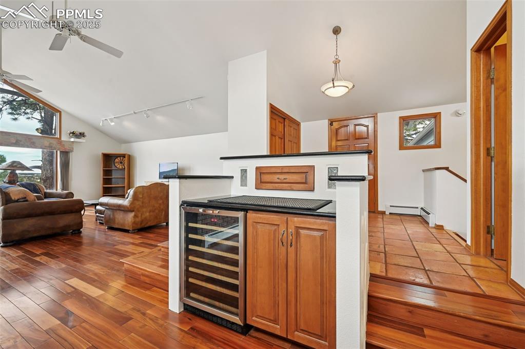 Image 27 of 49: Bar featuring track lighting, beverage cooler, brown cabinetry, dark wood-s