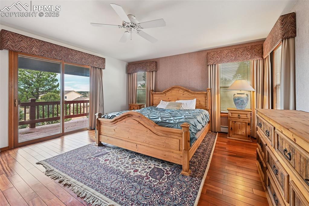 Image 29 of 49: Bedroom with multiple windows, access to exterior, ceiling fan, and hardwoo
