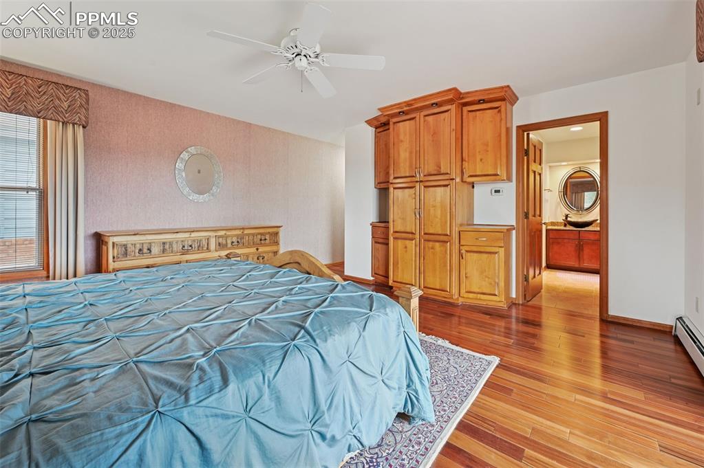 Image 30 of 49: Bedroom with light wood-type flooring, a ceiling fan, ensuite bath, and wal