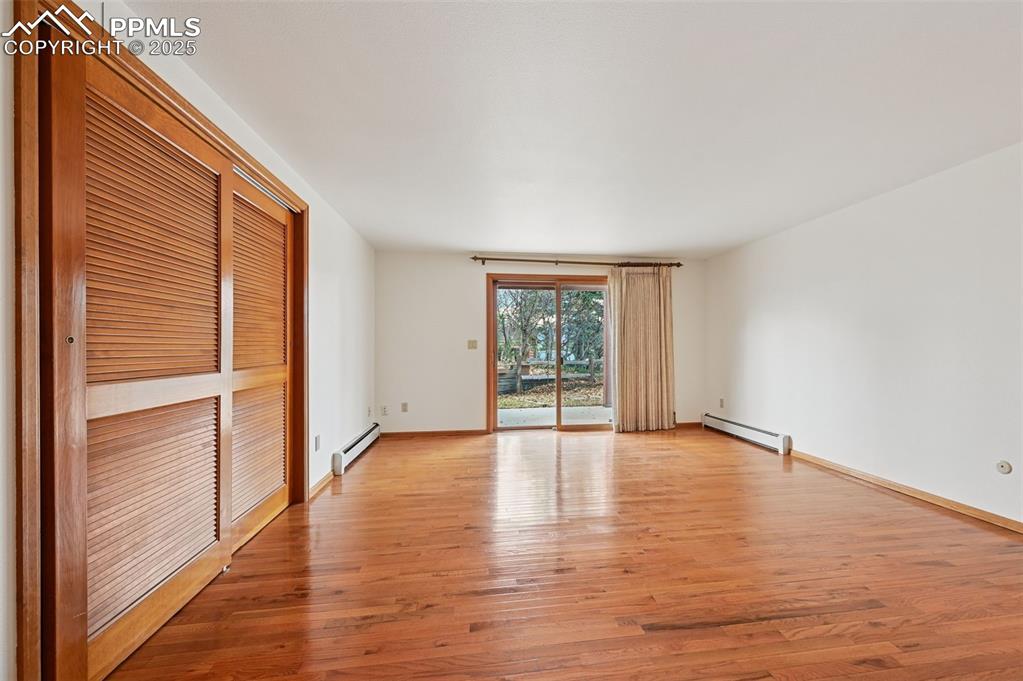 Image 38 of 49: Empty room featuring light wood-style floors and a baseboard radiator
