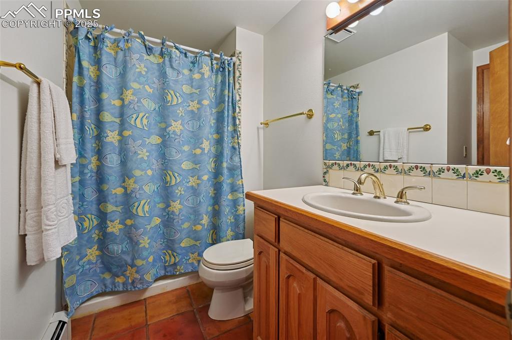 Image 39 of 49: Bathroom with vanity, dark tile patterned floors, a shower with shower curt