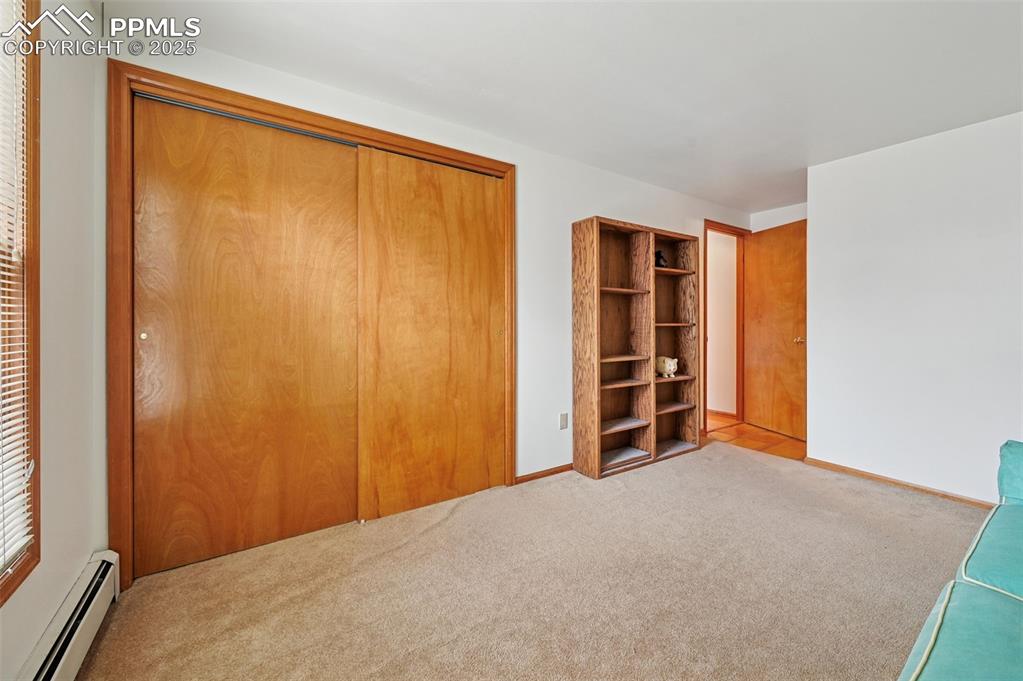 Image 40 of 49: Unfurnished bedroom with a baseboard heating unit, a closet, and carpet