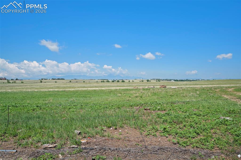 Image 12 of 50: Expansive open field with natural grass and distant mountain ranges under a