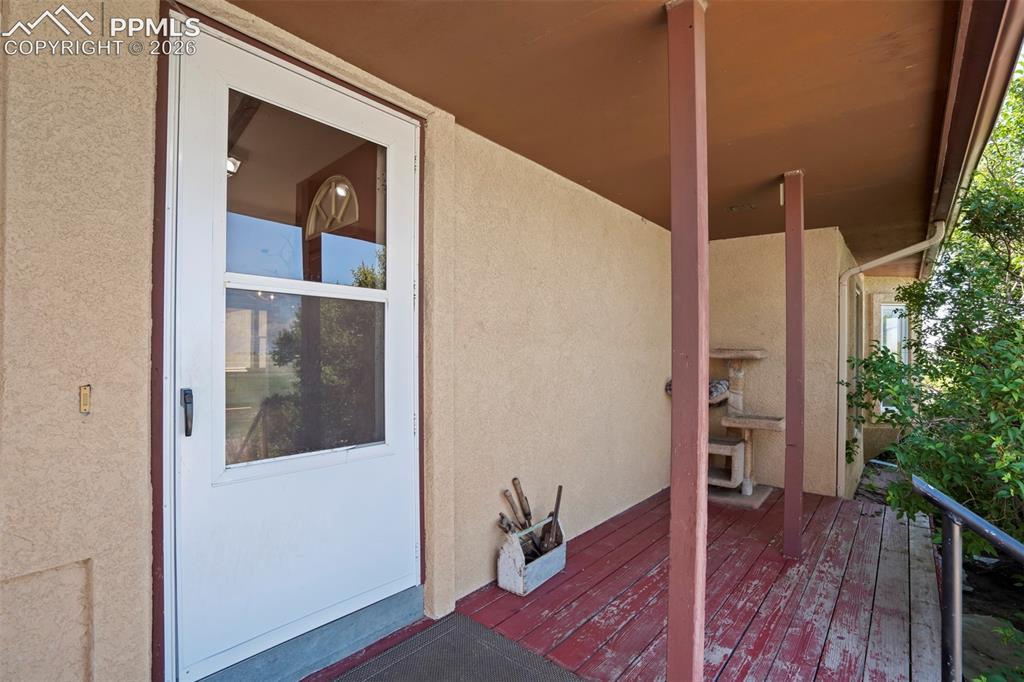 Image 13 of 50: Covered front porch featuring a full-view storm door, textured stucco exter